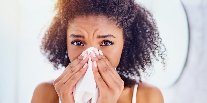 Women blowing nose into tissue because of allergies