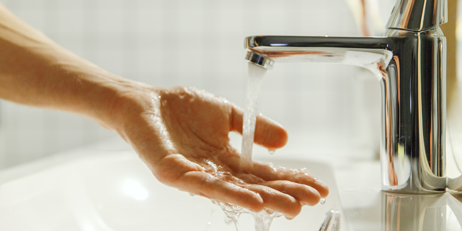 Man washing hands in hot water - Comparing Hot Water Tanks vs. Tankless Water Heaters: A Complete Guide for Homeowners
